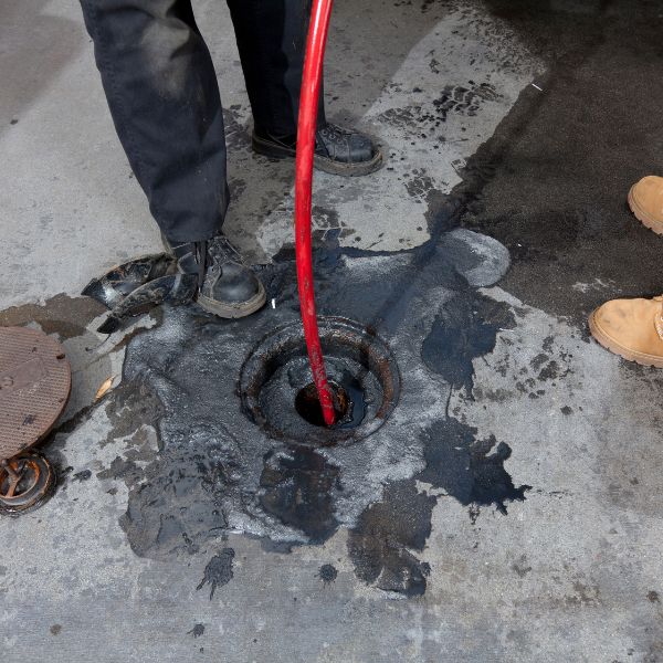 Using a hydro jet to clean a clogged drain.